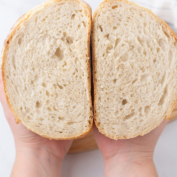 Image of hands holding 2 slices of buttered white sourdough.