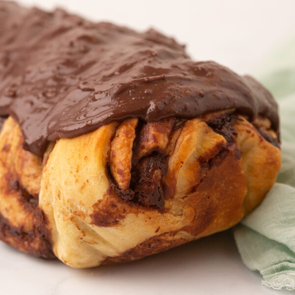 Image of a warm chocolate swirled roll of babka bread with a chocolate glaze on the top