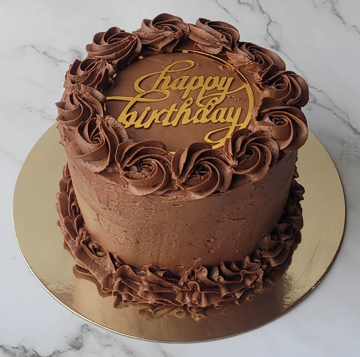 Decadent chocolate birthday cake topped with decorative chocolate buttercream icing.