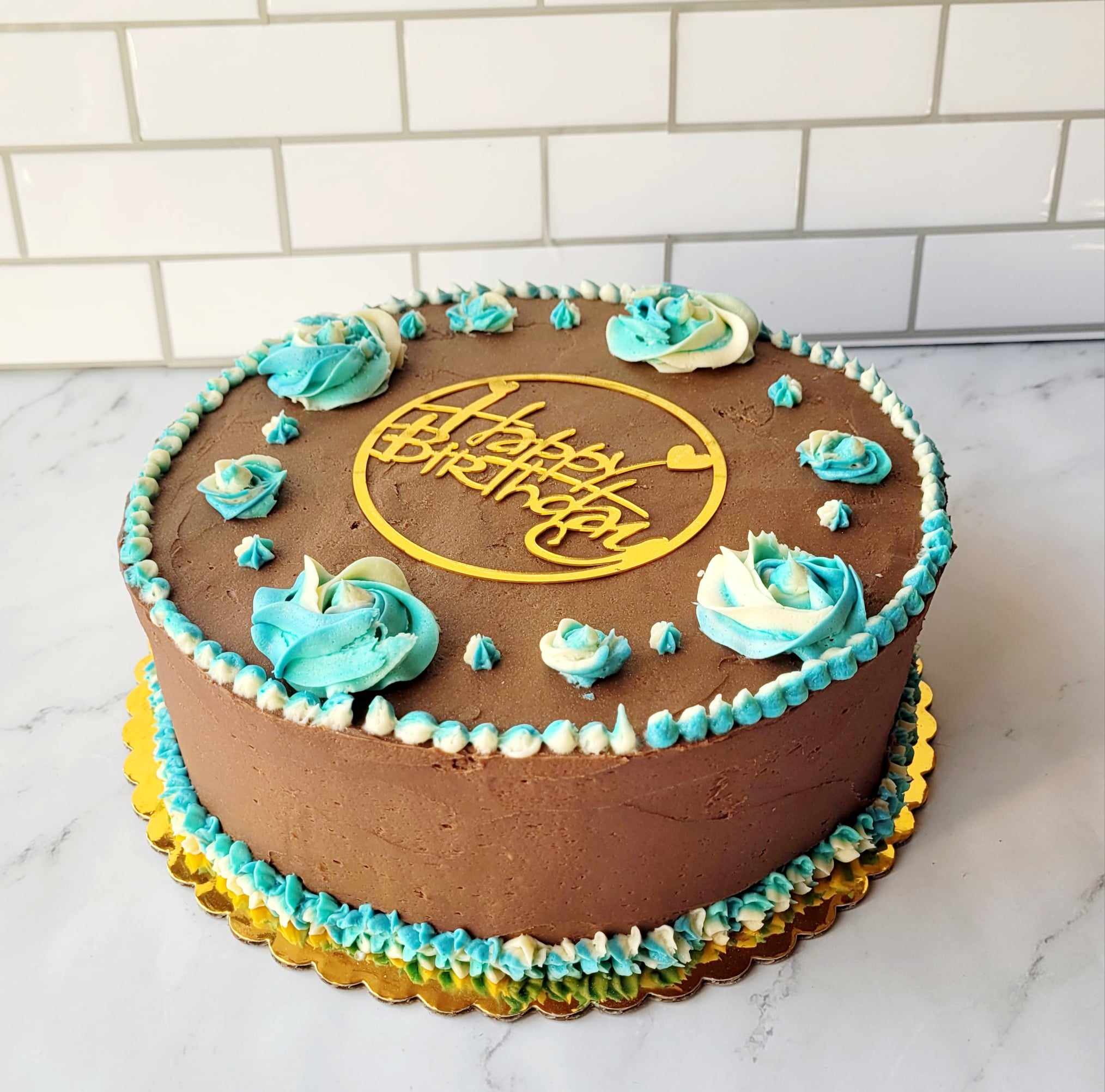 A decadent 9 inch 2 layer chocolate buttercream cake iced with small and large rosettes done win white and blue vanilla buttercream.